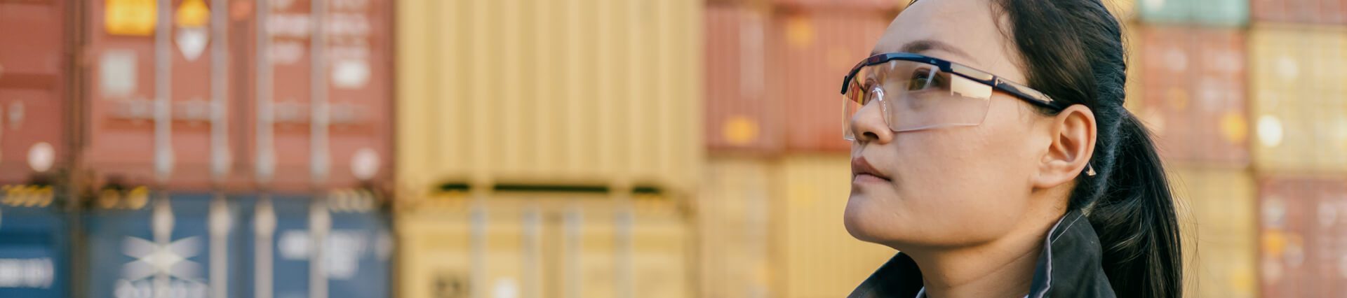 a woman wearing safety goggles and standing in front of containers