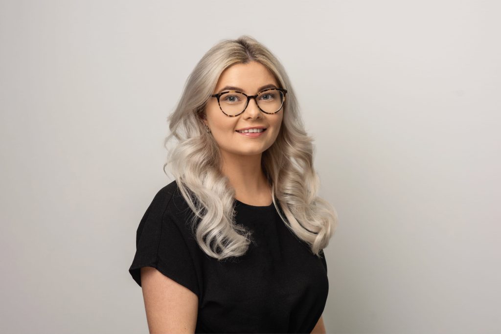 An image of Jess McDonald wearing a black top and smiling at the camera.