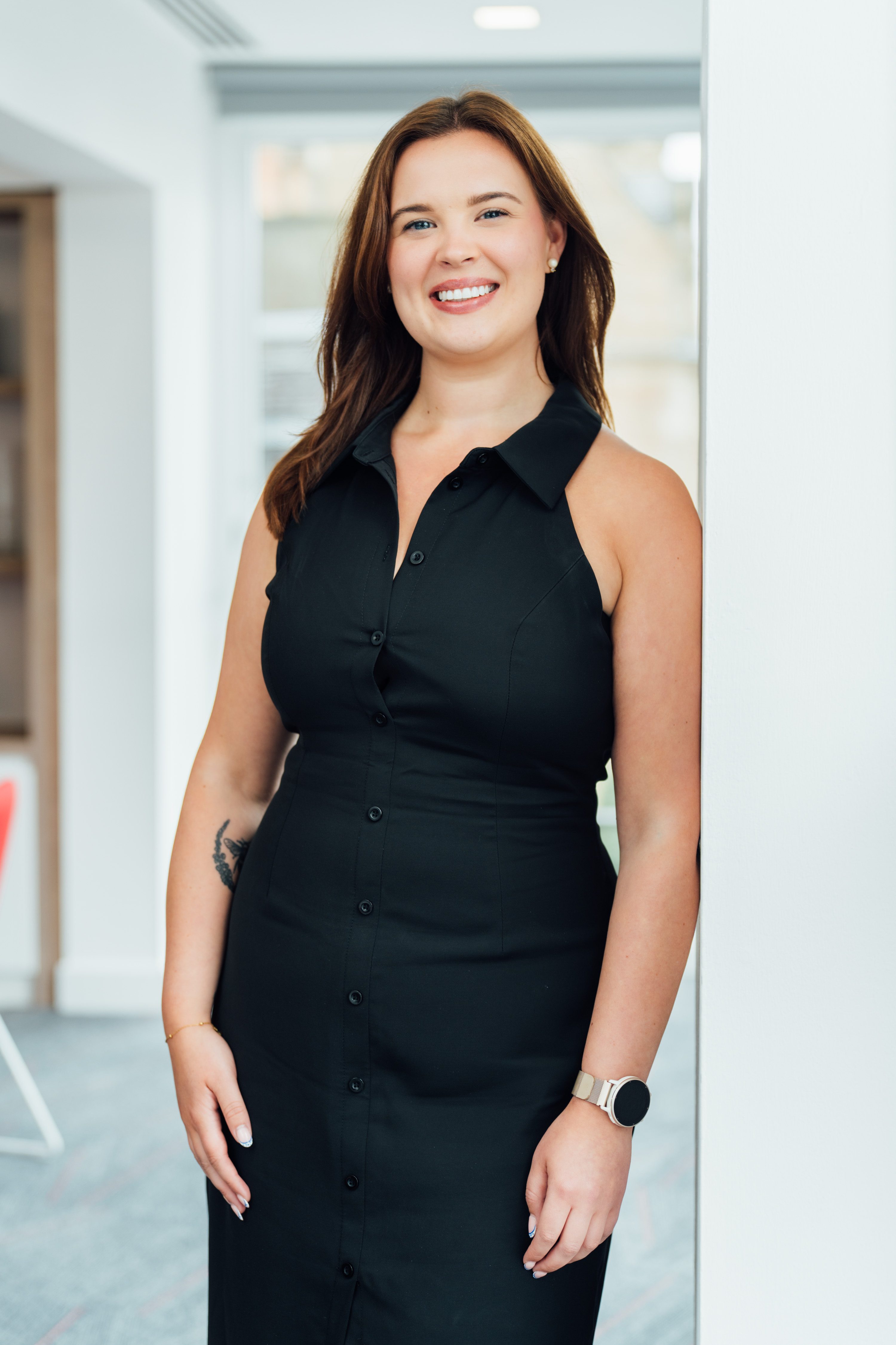 An image of Alex Brown wearing a black dress and smiling at the camera.