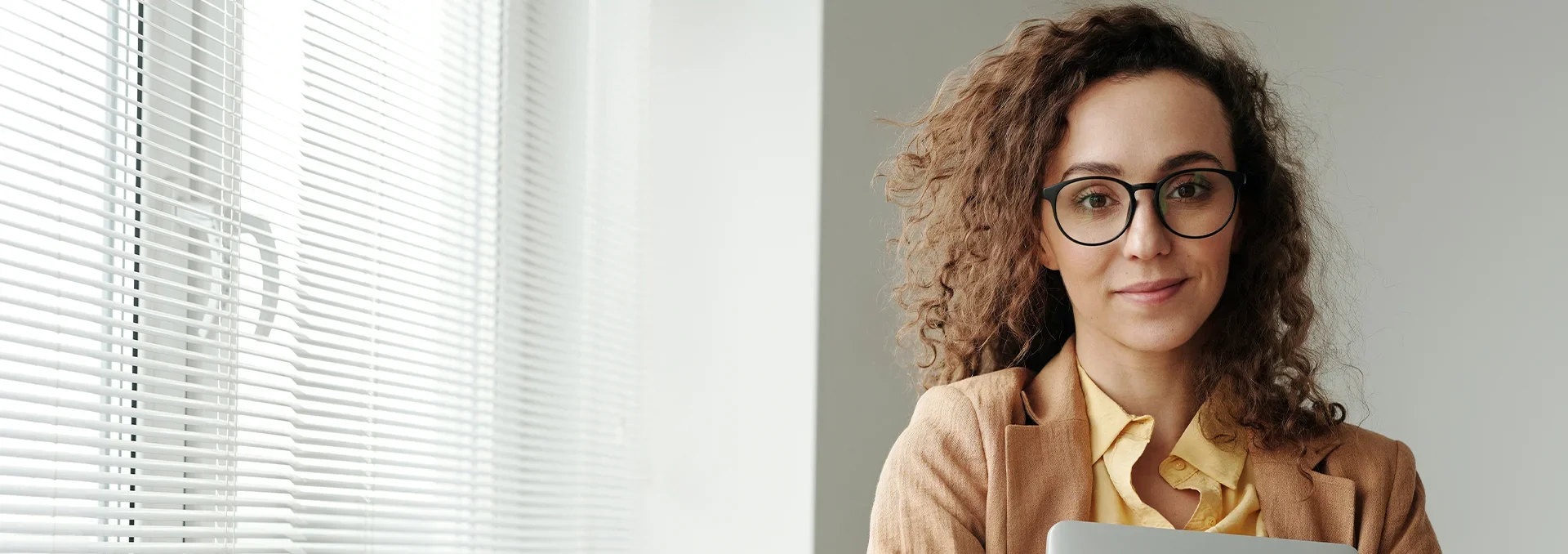 Fundraising for business services banner showing a woman with glasses and curly hair, holding a laptop in her hands
