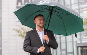 A AAB employee outside the Aberdeen office with a branded umbrella