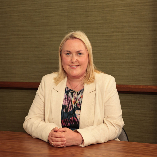 An image of Francine Smith wearing a yellow blazer and sitting at a desk.
