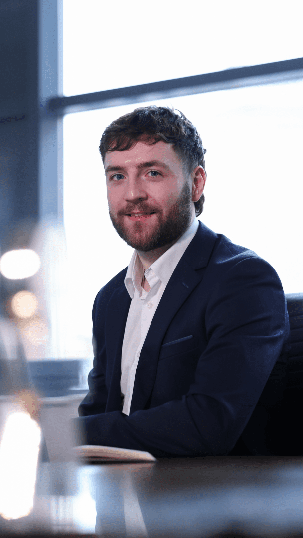 An image of Patrick McCullagh wearing a suit and sitting at a desk.