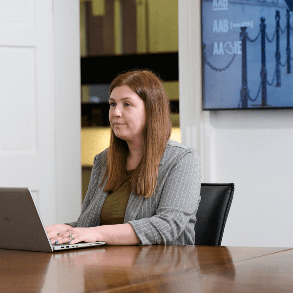 An image of Ellyn Higgins sitting at her desk on her laptop.