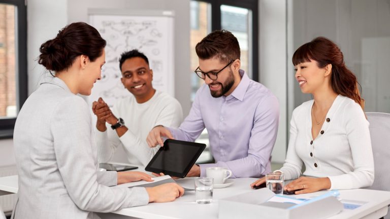 AAB employees sitting round a table with laptop in the office.