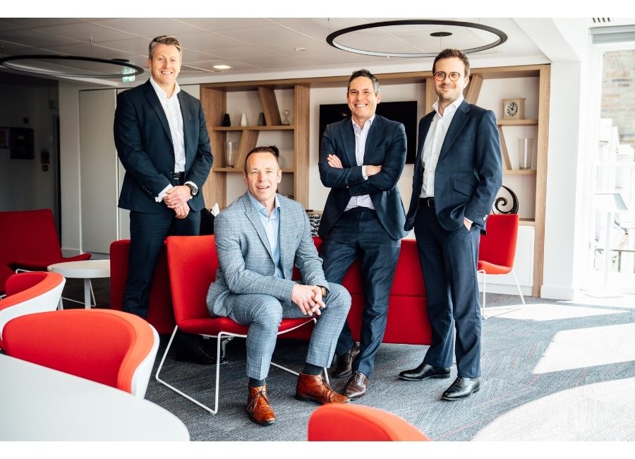 An image of four AAB team members sitting together in the AAB Edinburgh office wearing suits.