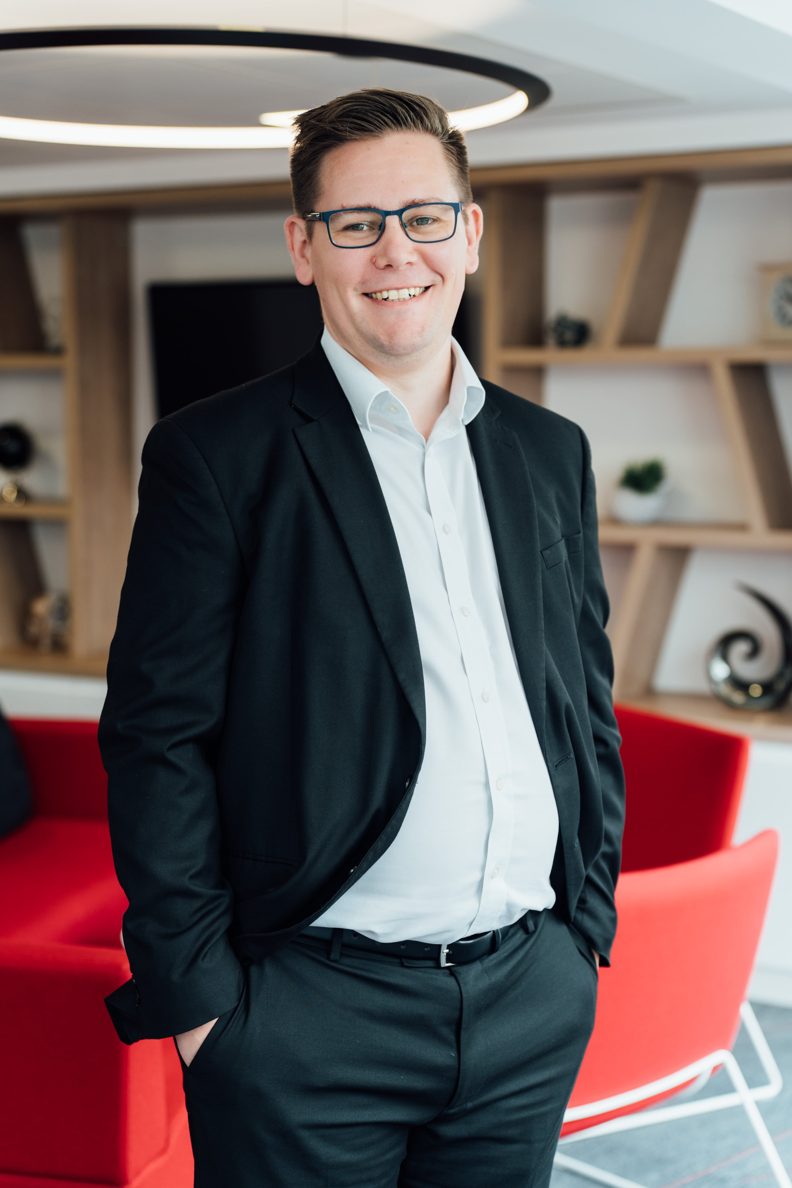 An image of Andrew Philbin wearing a suit with his hand in his pockets and smiling at the camera.