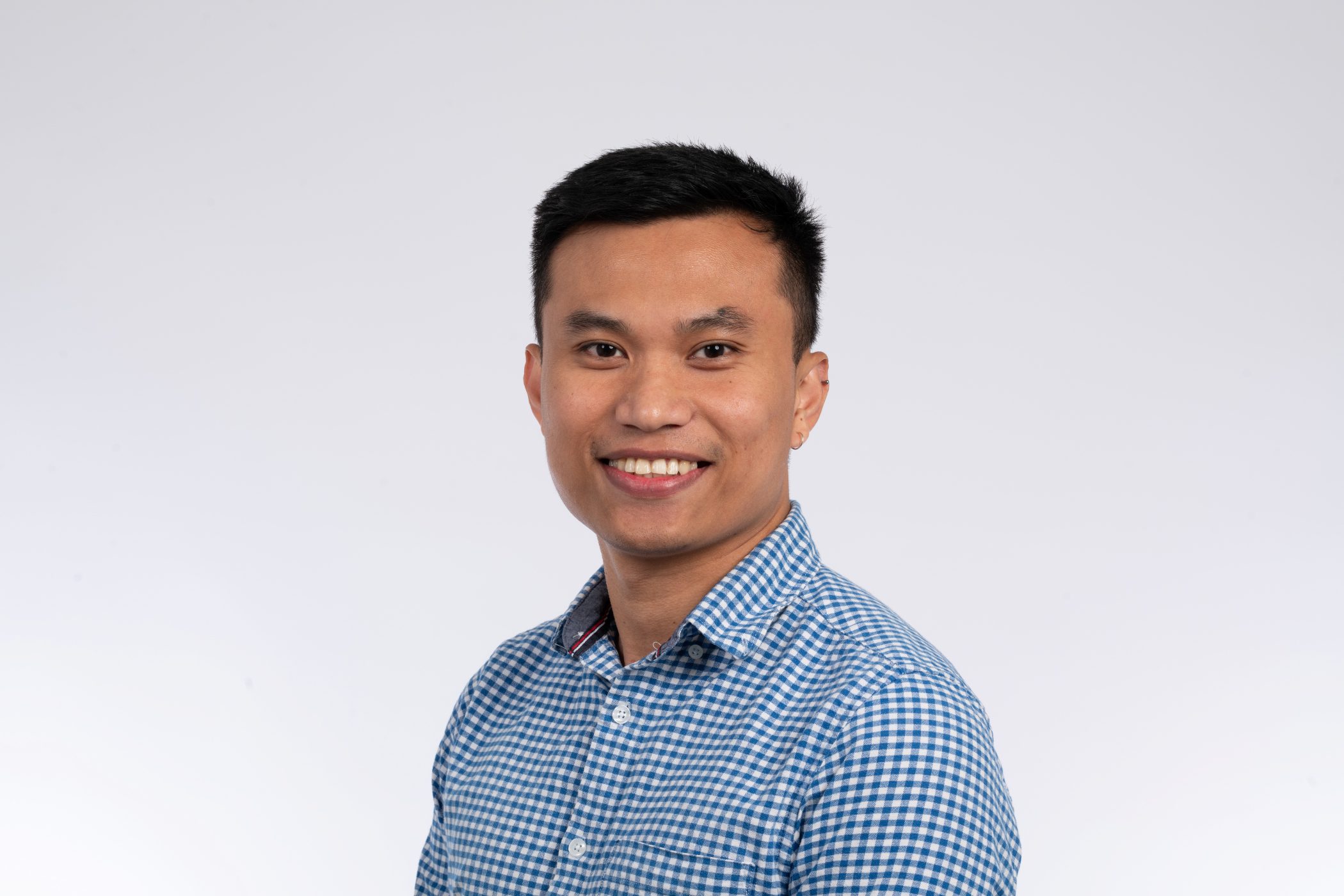 Amiel Malundas head and shoulder shot, smiling at the camera against a dust coloured background