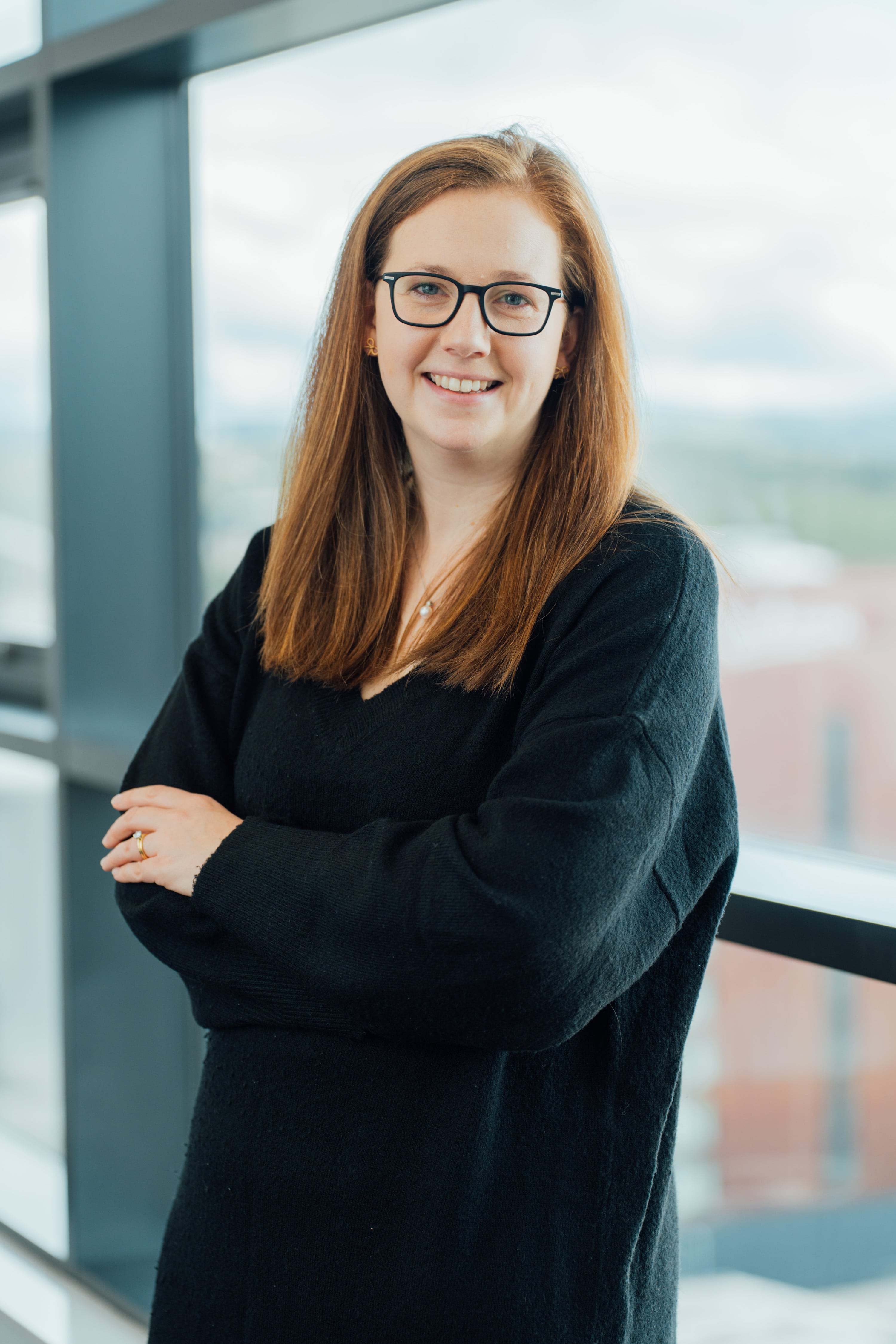 An image of Catherin Teenan wearing a black top, with her hands crosses and leaning against the windowsill.
