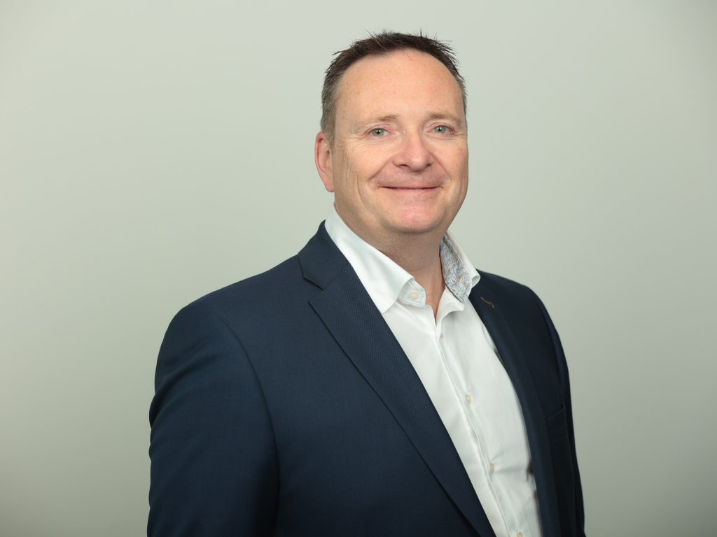 A headshot image of Dante Peters wearing a white shirt and navy suit.