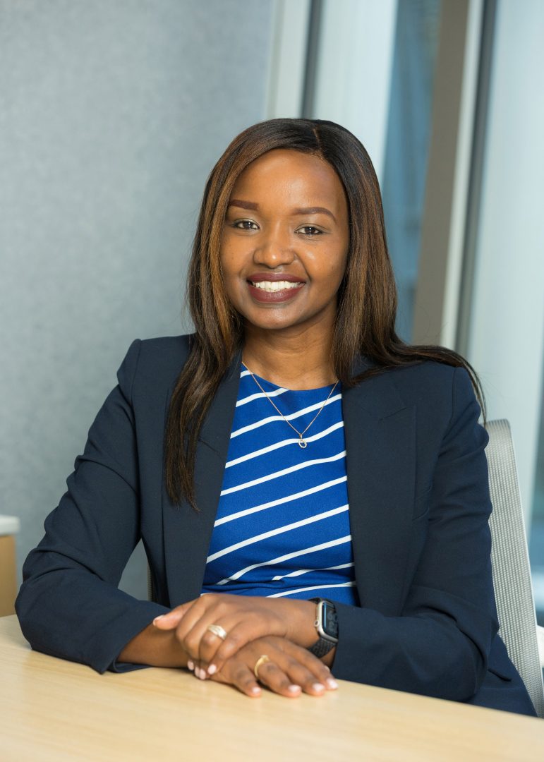 Linet Kiilu sitting at a desk smiling with her hands crossed