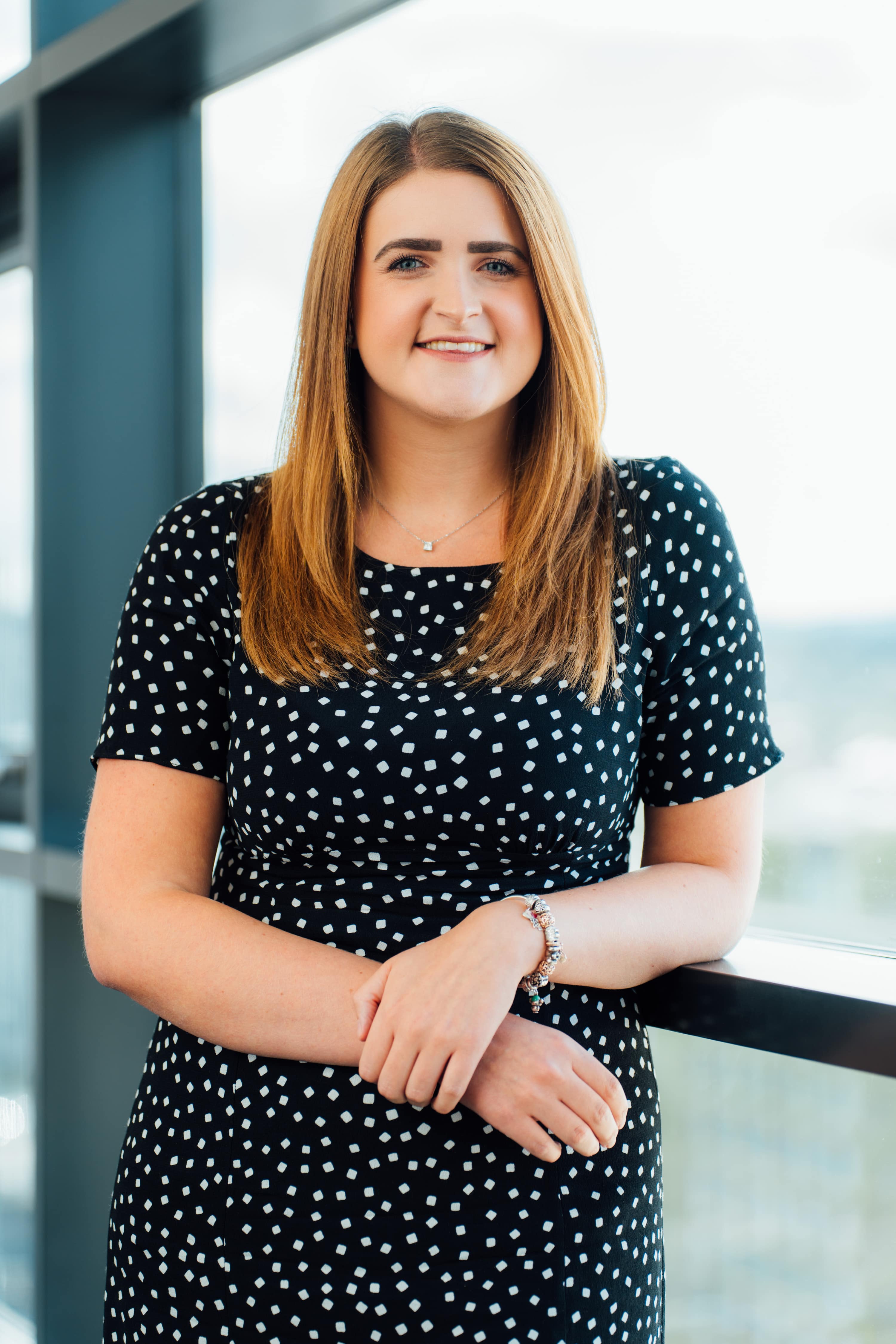 An image of Stephanie Lalley leaning against a window wearing a polka dot dress.