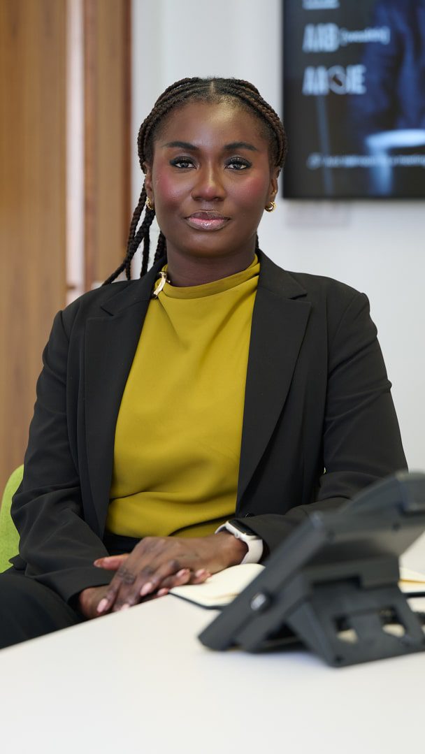 An image of Rosemary Addo sitting at her desk with her telephone.