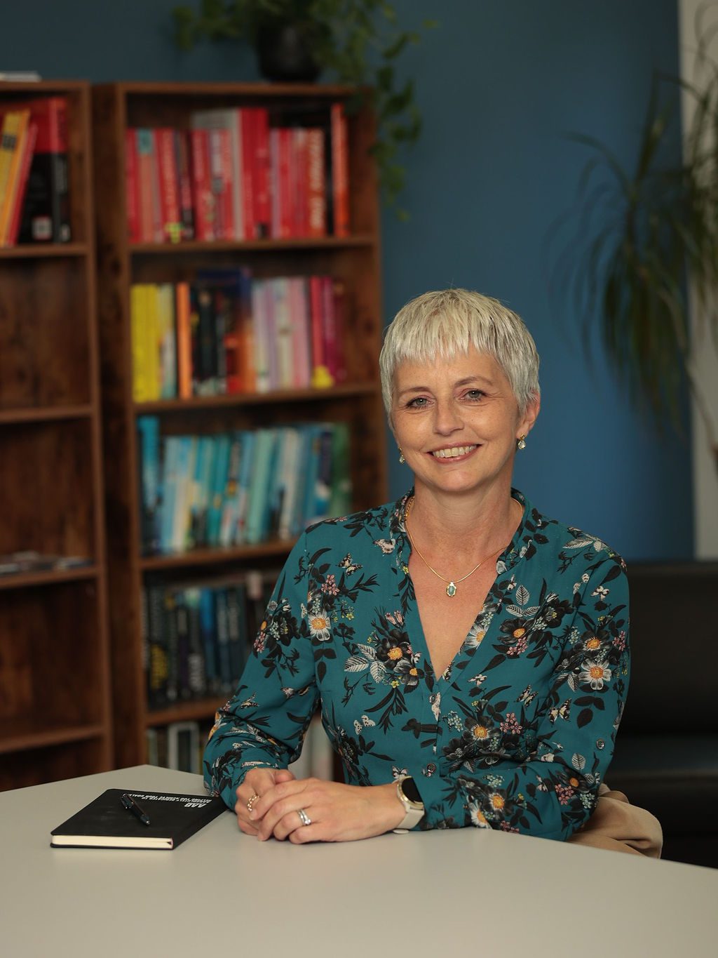 An image of Amanda Hayes sitting at a desk in the office and wearing a blue top.