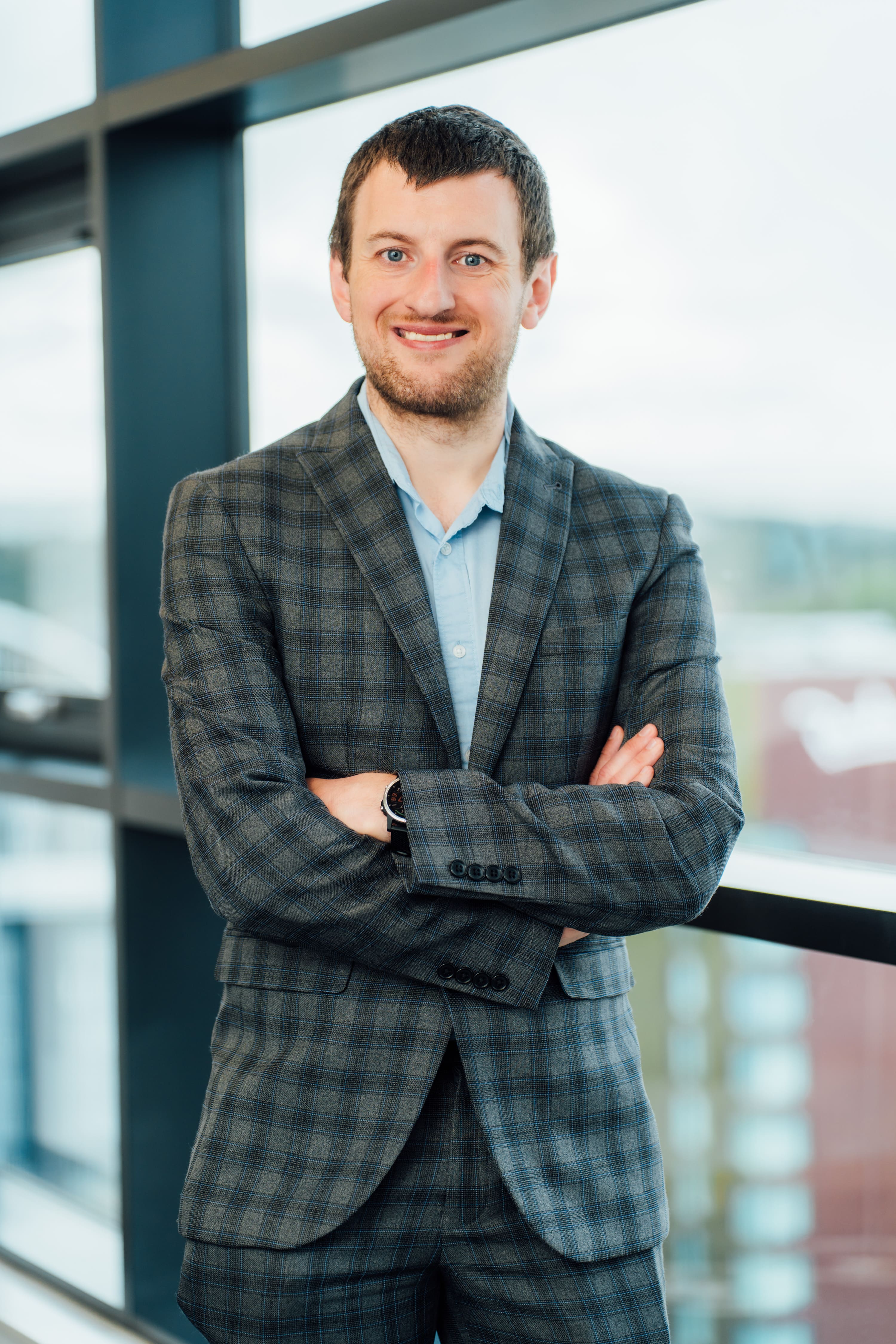 An image of Iain Littler wearing a suit and with his arms crossed and smiling at the camera.