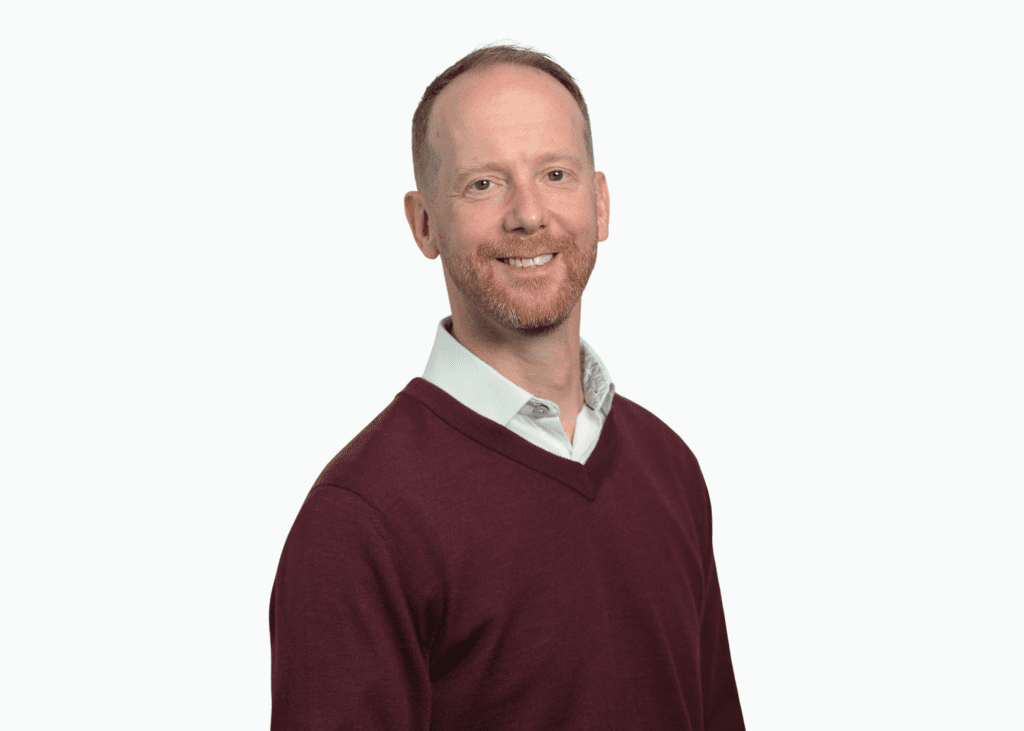 A headshot image of Jamie Stanford wearing a shirt and jumper.