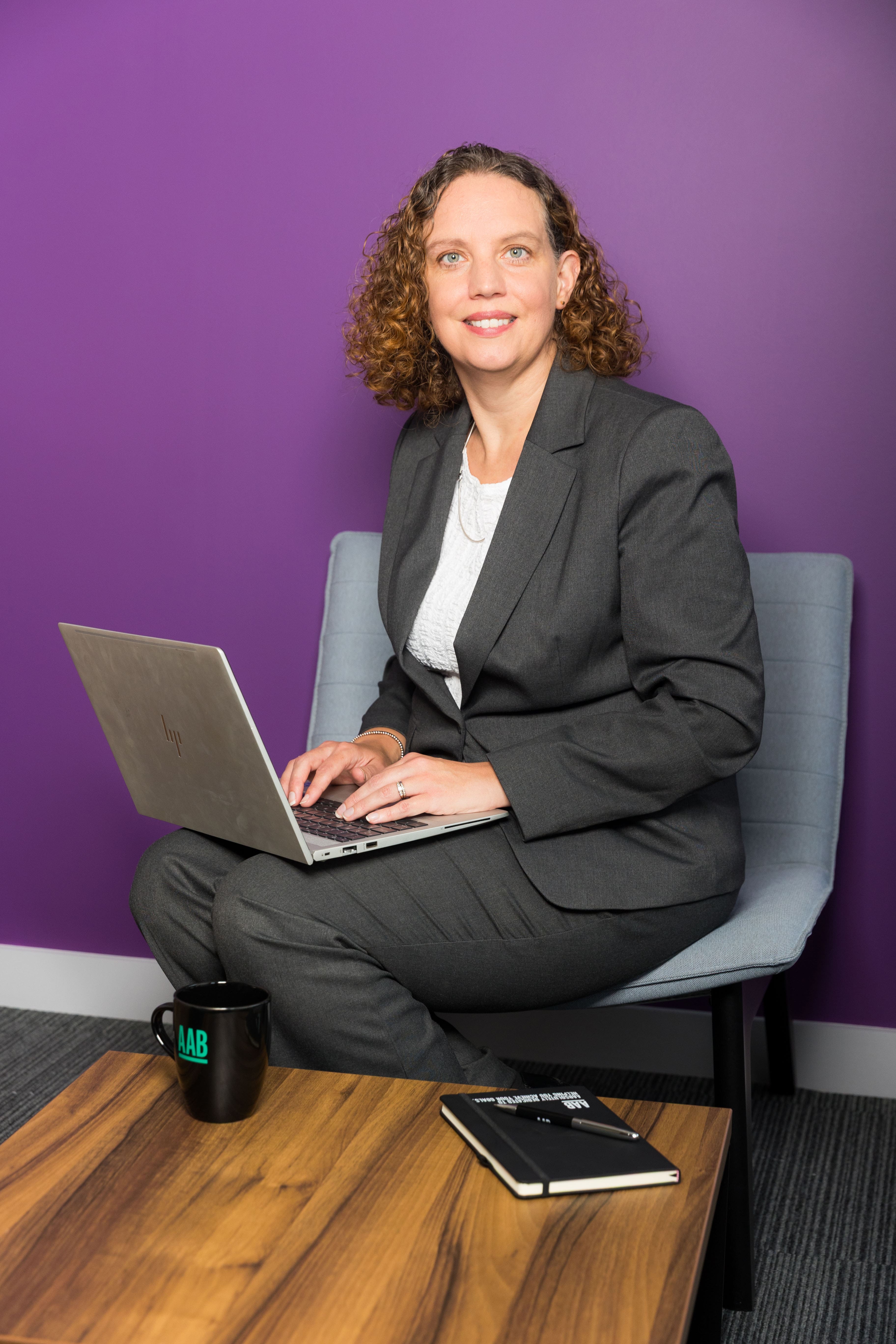 An image of Jenny Hampton wearing a suit jacket and working on her laptop.