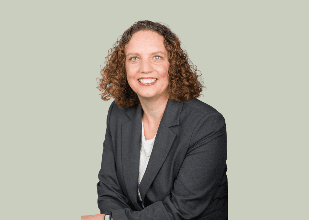 An image of Jenny Hampton wearing a grey suit jacket and smiling at the camera.
