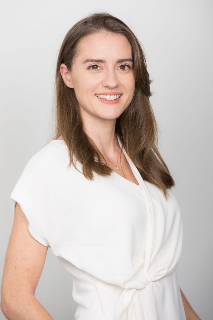 An image of Lizzy Hollamby wearing a white top and smiling at the camera.