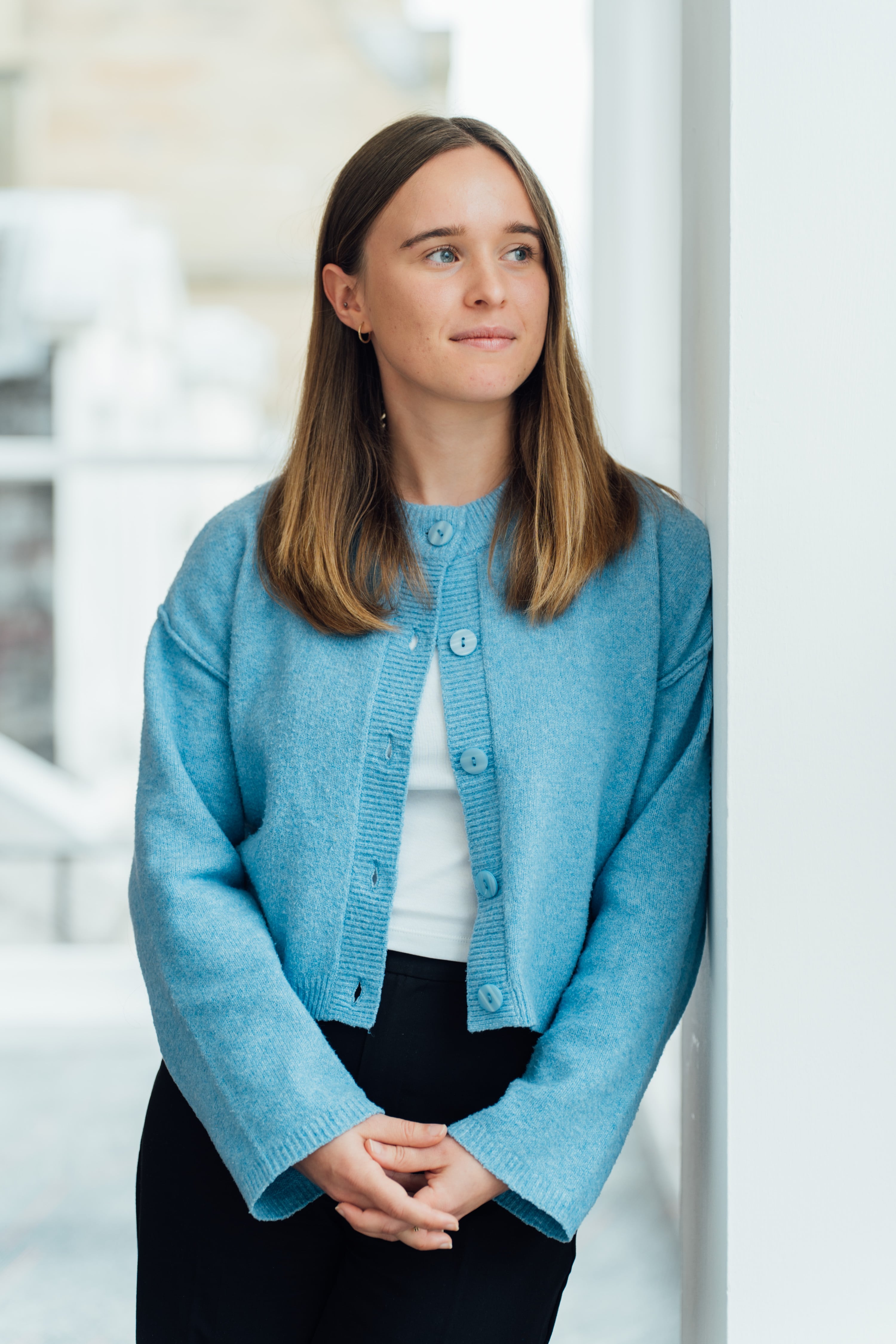 An image of Louise Neilson looking out a window and wearing a blue cardigan.
