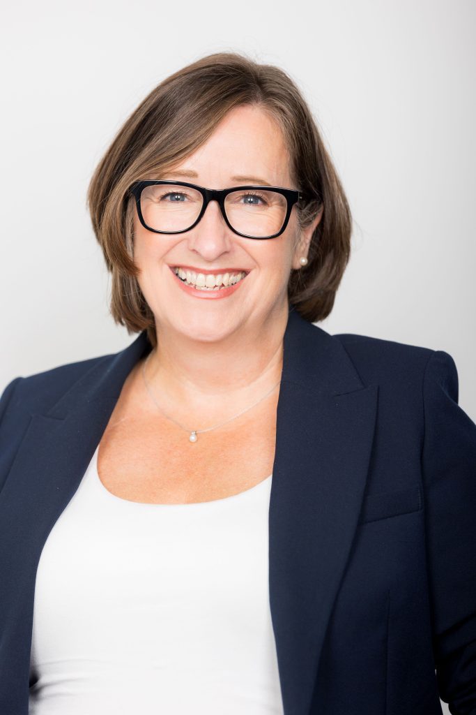 An image of Sharon Taylor wearing dark glasses and smiling at the camera.