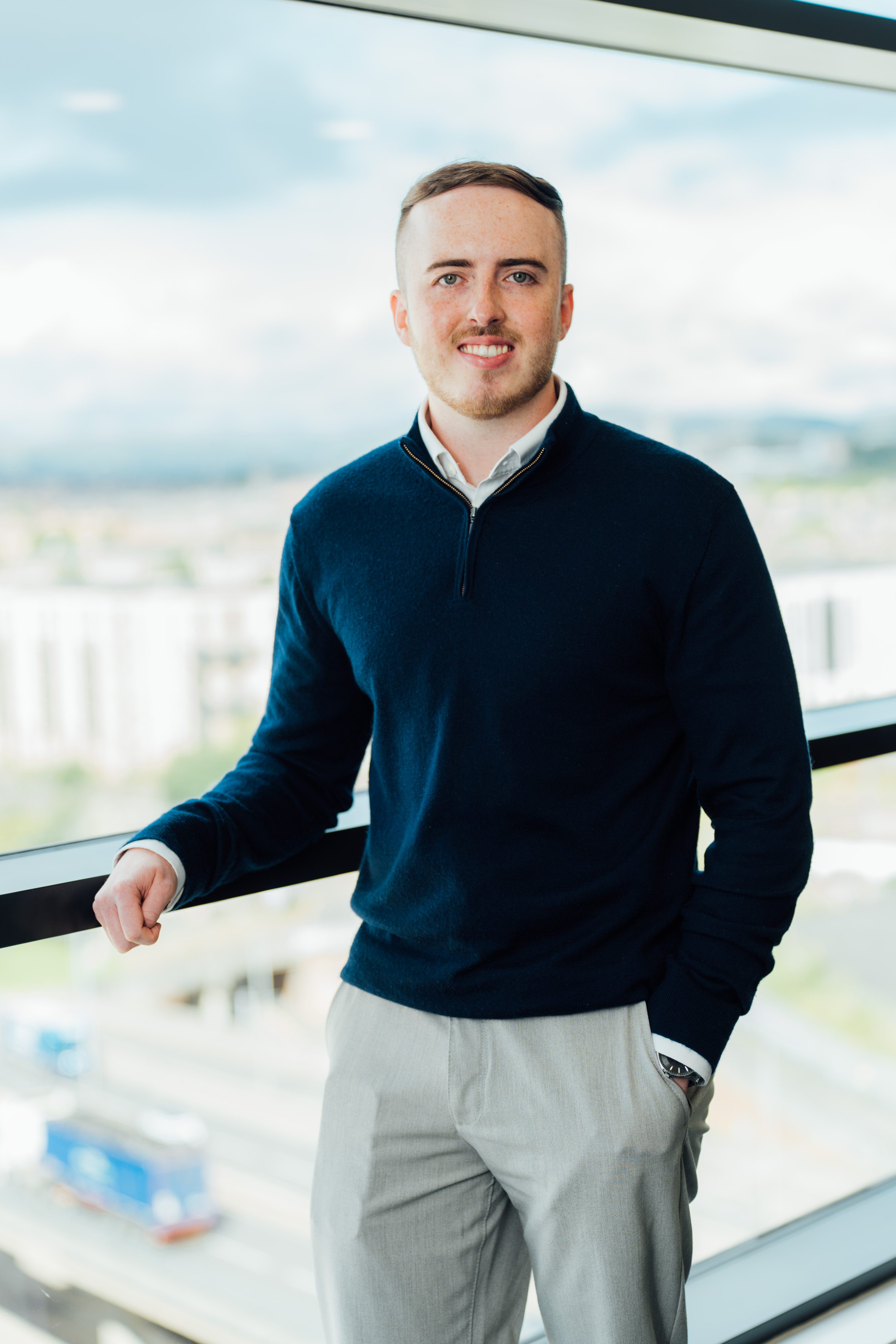 An image of Lewis Handley standing next to the window with his hand in his pocket.