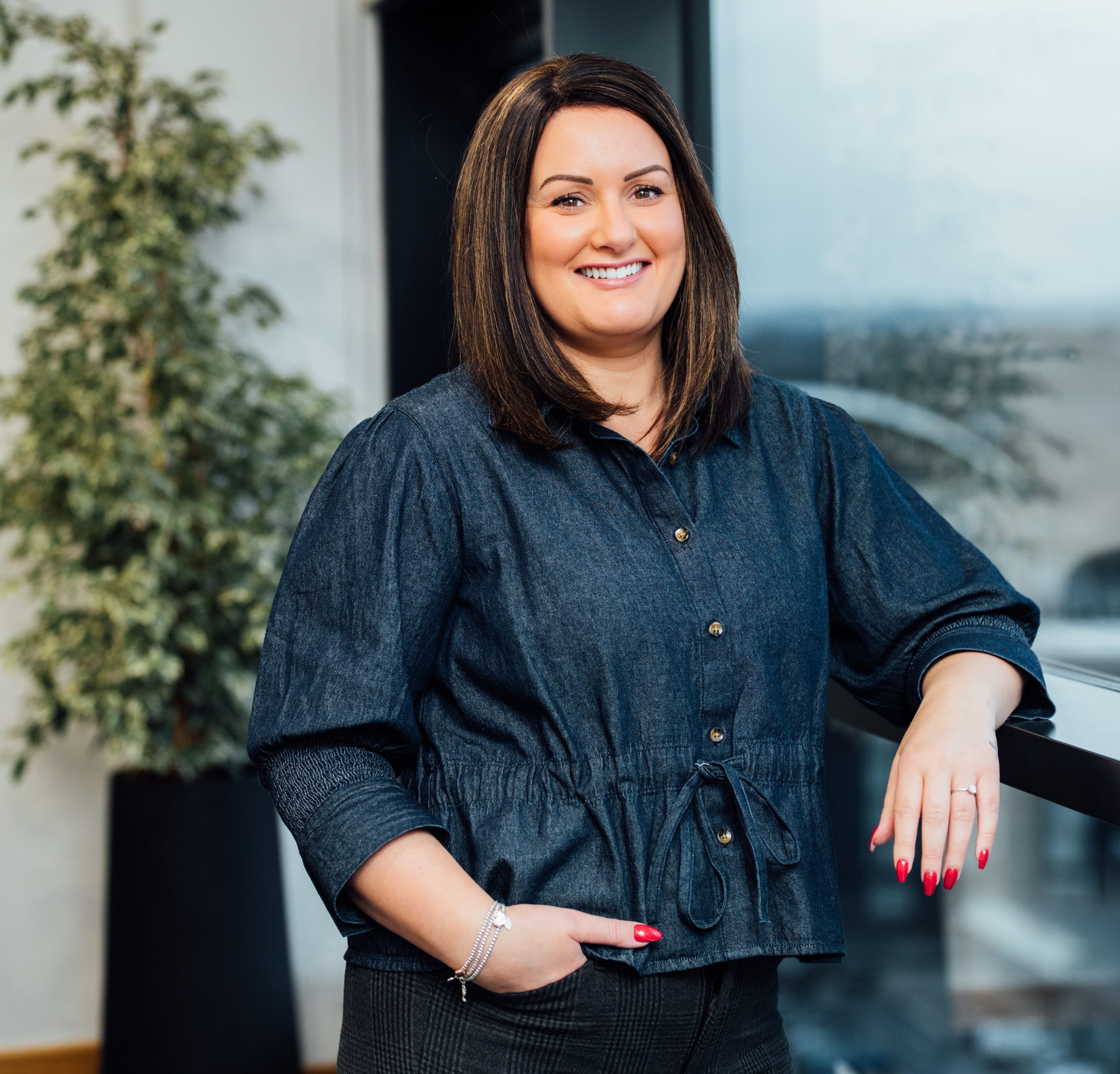 An image of Nicola Noble wearing a blue top and standing next to the window.
