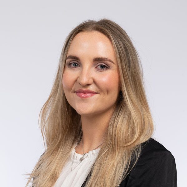 Katie Coleby smiling while sitting at an angle.