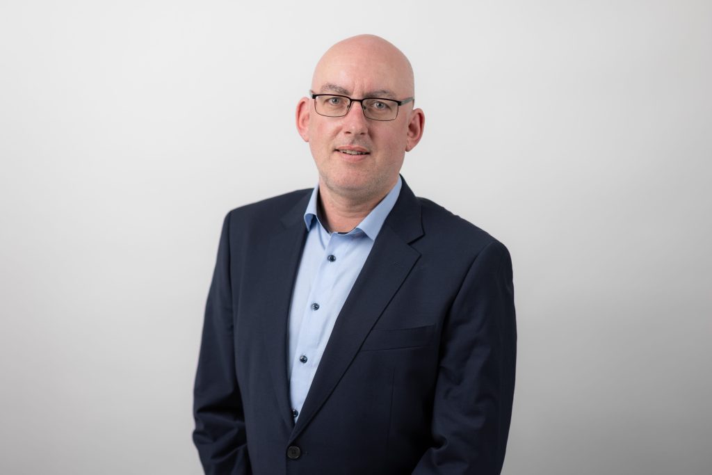 An image of Aidan McGrath wearing a shirt and blazer.