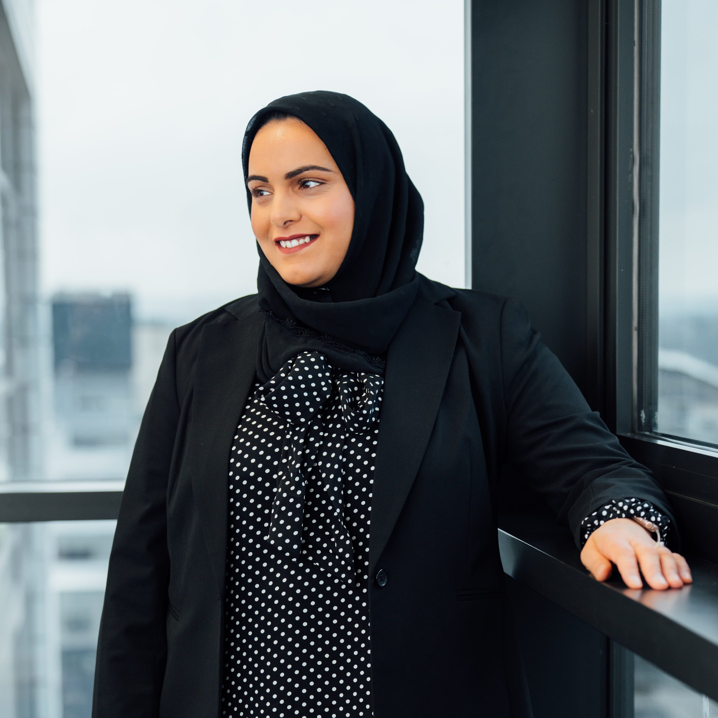 An image of Aishah Akhtar standing in the office next to the window.
