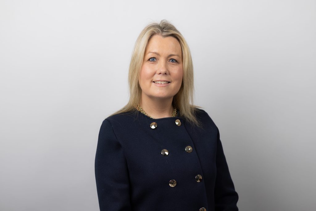 An image of Lynn Honer wearing a black top and smiling at the camera.