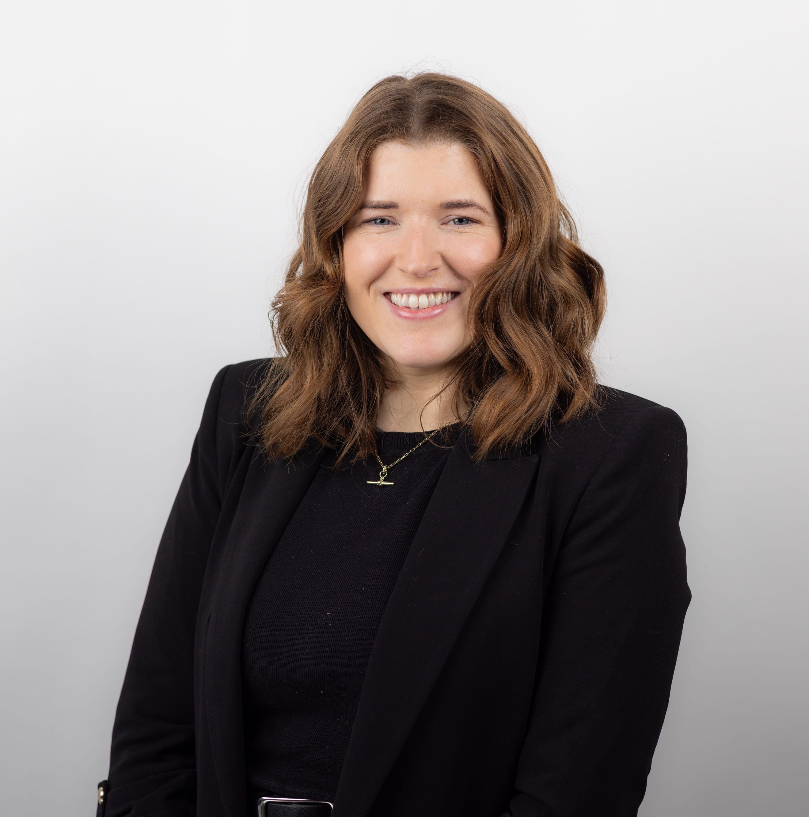 An image of Niamh Ryan wearing a black outfit and smiling at a camera.