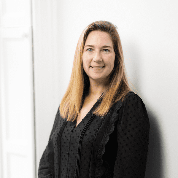 An image of Rachel Barry wearing a black dress and smiling at the camera.