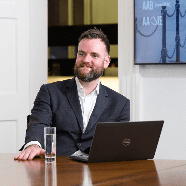 An image of Robert Wilson wearing a black jacket and white shirt.