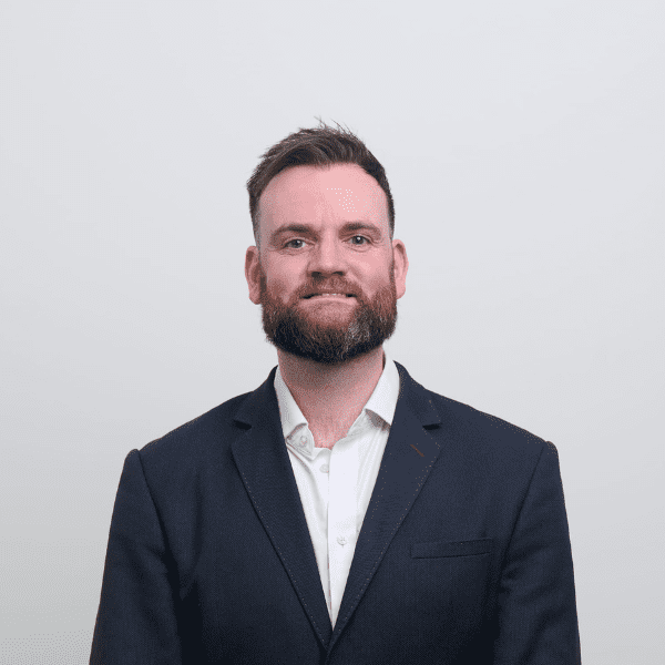 An image of Robert Wilson wearing a black jacket and white shirt.