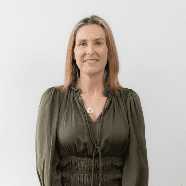 An image of Sylvia Stanbridge wearing a green dress and smiling at the camera.