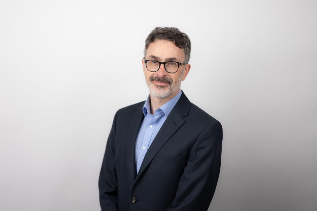 An image of Darren Benham wearing a black suit jacket and blue shirt.