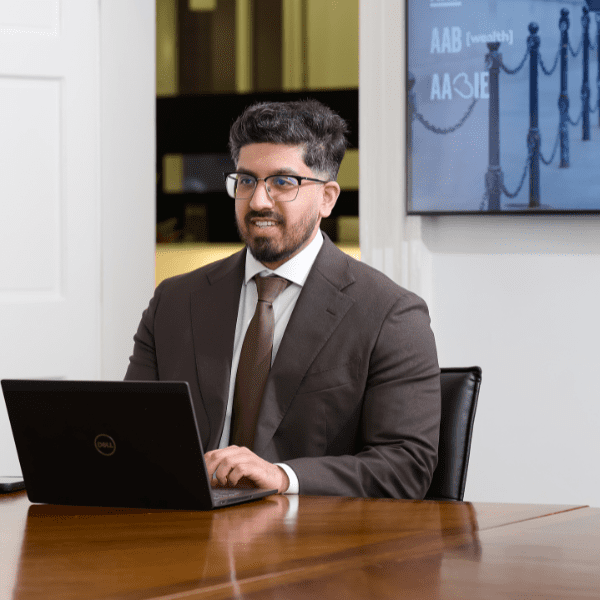 An image of Rafiq Gazi sitting at a desk with his laptop and smiling at the camera.