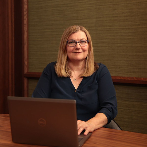 An image of Sarah Louw sitting in the office on her laptop,