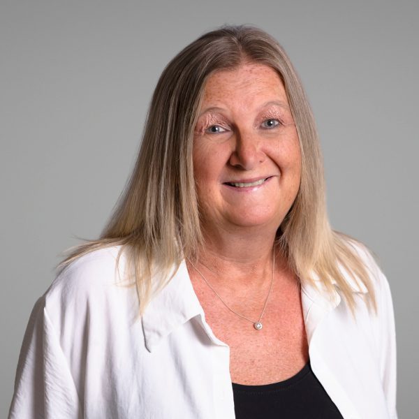 An image of Karen Lane wearing a white cardigan and black top. She is smiling at the camera.