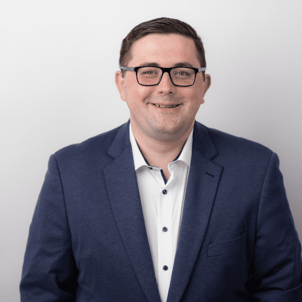 An image of Thomas Byrne wearing a suit jacket with a shirt.