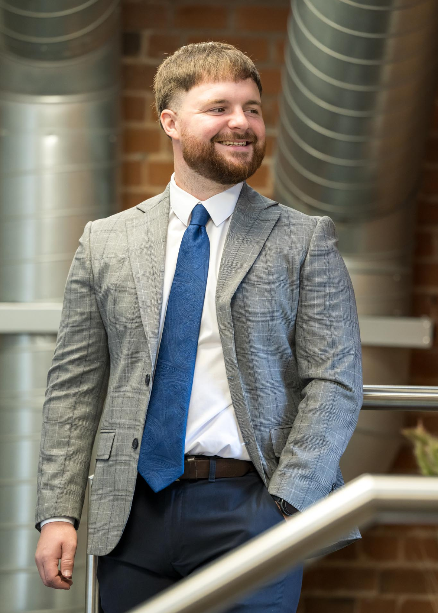 Daniel Osborne, Senior Accountant at AAB stood on a small staircase with brick wall behind