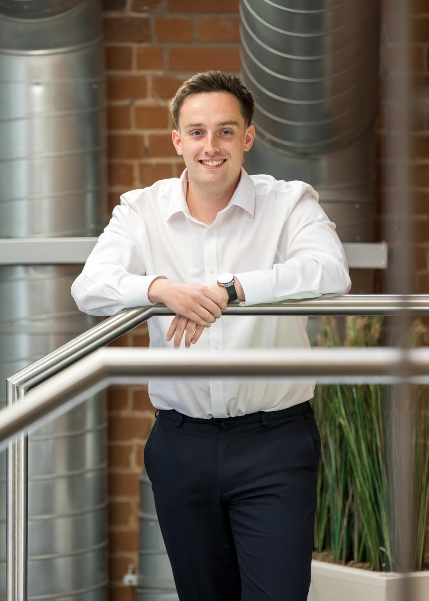 Dominic Dineen Corporate Director of AAB leaning against a clear glass banister in an office setting