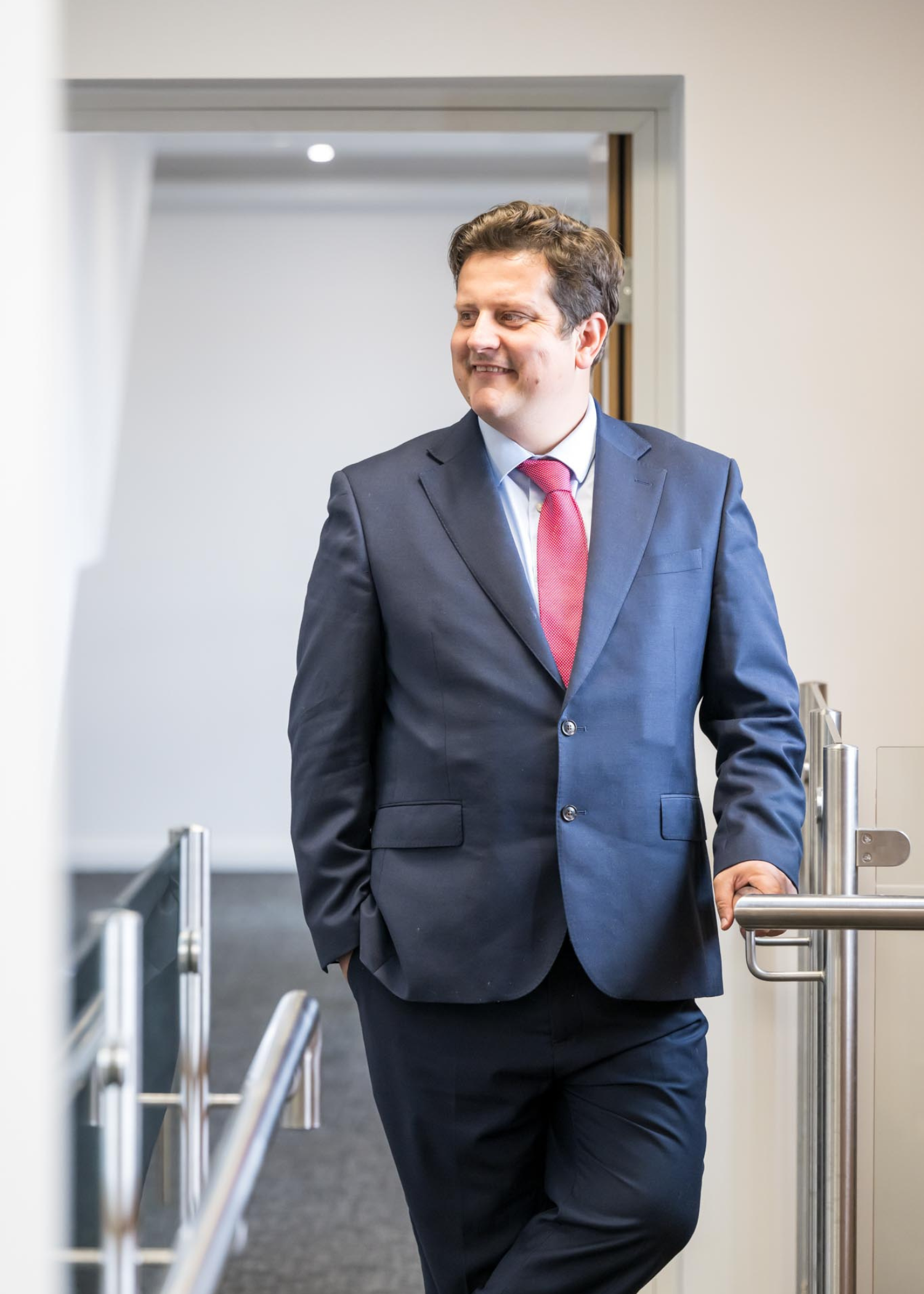 Nicholas Griffin Commercial Director of AAB leaning against a banister in a white corridor in an office