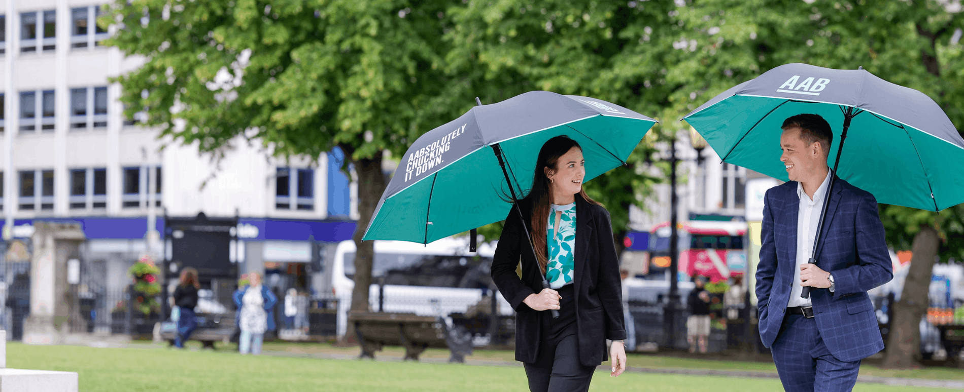 AAB employee walking with umbrellas hero banner.