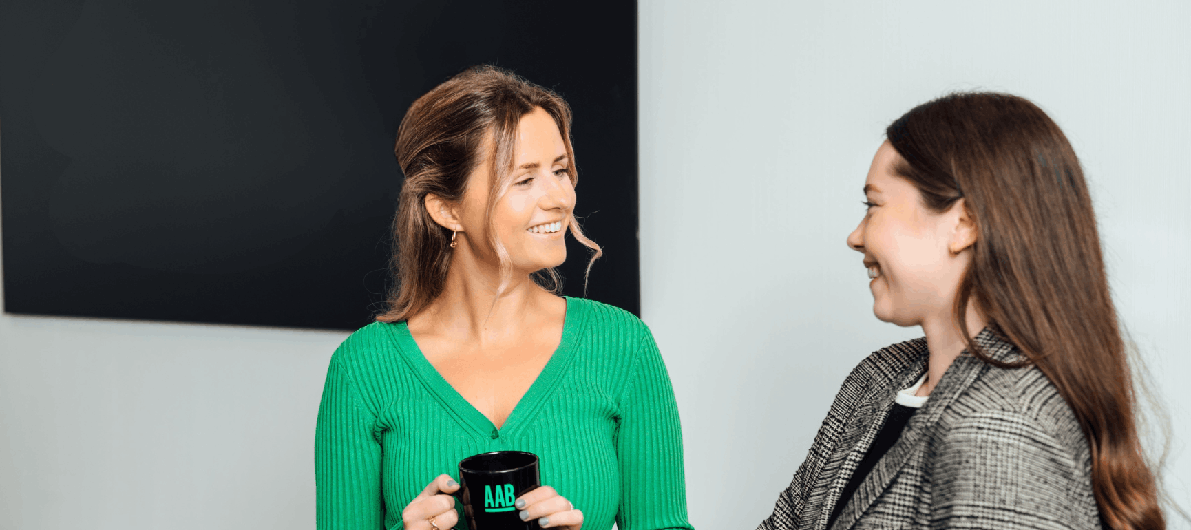 An image of Charlotte Robertson smiling at Zoe Dollard. She is holding a mug.