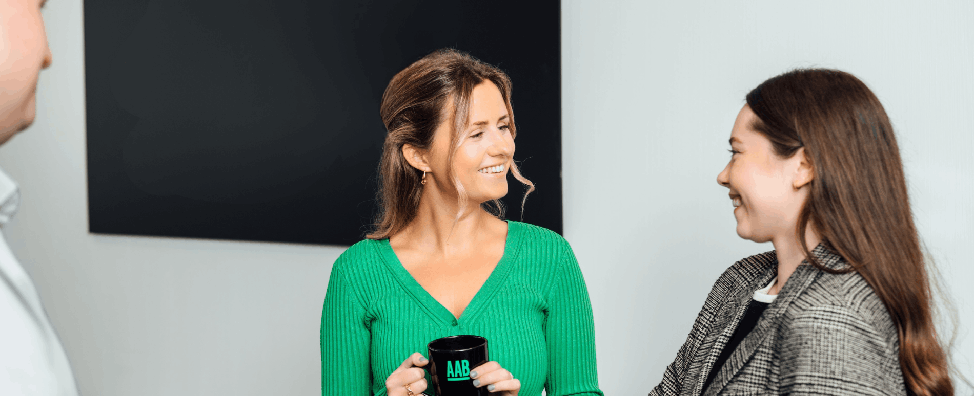 An image of Charlotte Robertson smiling at Zoe Dollard. She is holding a mug.