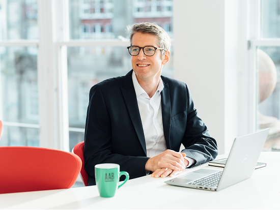An image of a team member sitting at a desk and smiling at the camera.
